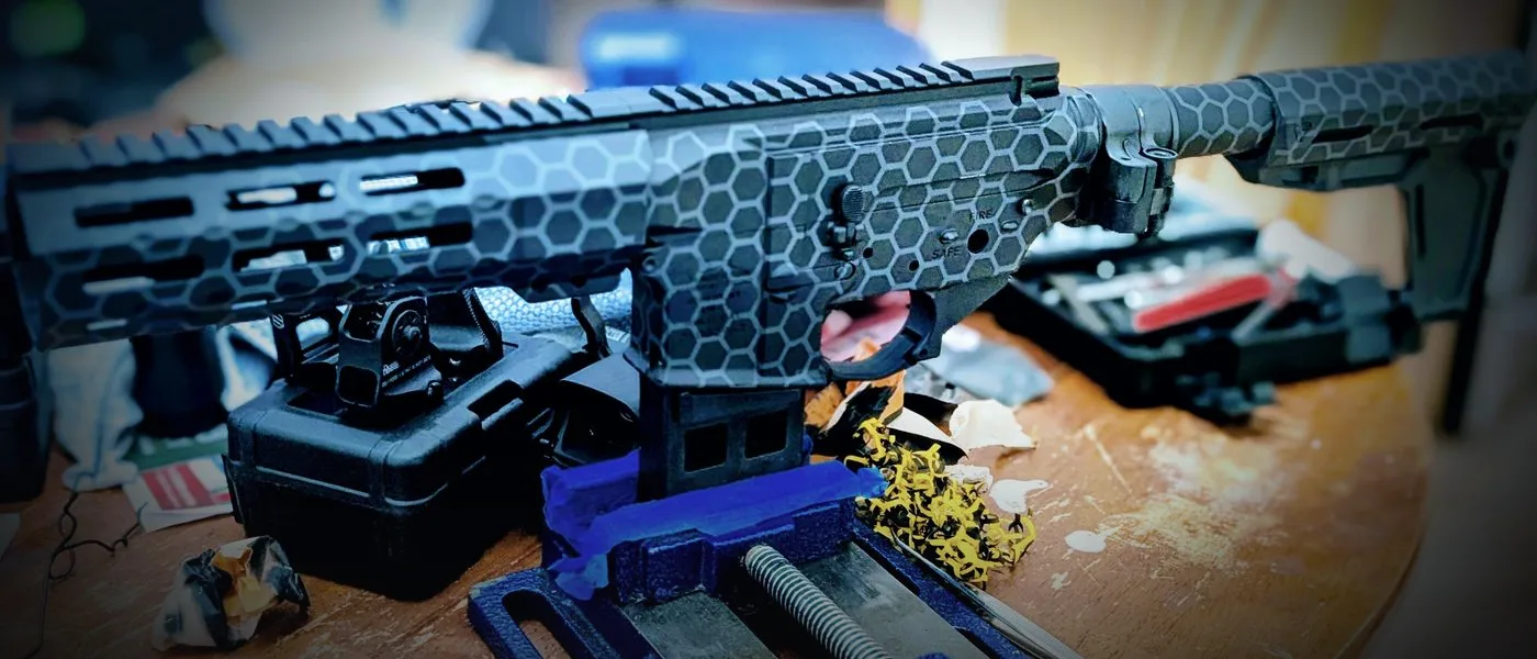 A hex-pattern Cerakoted AR-15 build clamped in a bench vise in the Hearth to Forge workshop